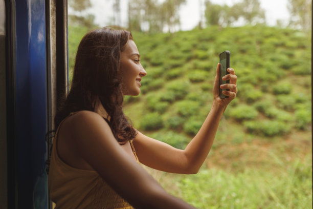 女人从火车窗外拍摄绿茶种植园的照片图片下载