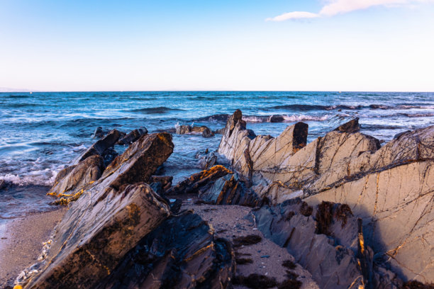 美丽的海岸上有锋利的石头，被海浪冲刷。荒野海滩上的石脊。光滑而长的石头形成延伸入海。美丽的海洋自然照片。图片下载