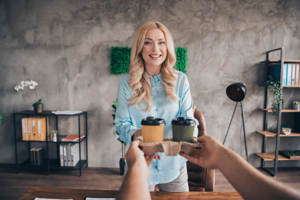 成功的职场女性从咖啡外卖员那里接收咖啡的第一人称视角照片，现代阁楼室内办公室环境。图片下载