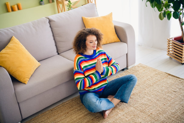 全景高角度照片，漂亮的年轻女孩坐在地板上冥想，现代室内公寓环境。图片下载