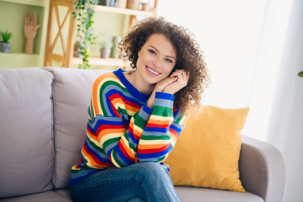 年轻女孩坐在沙发上，穿着毛衣，现代室内公寓内的照片图片下载