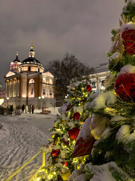 城市夜晚的圣诞树上闪烁着明亮的灯光、花环和装饰，手机拍摄的照片图片下载