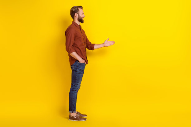 满意乐观的男性侧面照片，穿着酒红色衬衫，面向空白空间，准备握手，背景为黄色。图片下载