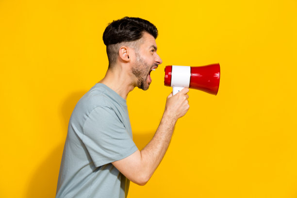 愤怒的男孩老板侧面照片，穿着时尚的卡其色衣服，空旷的空间中大喊“快点”，背景为黄色。图片下载