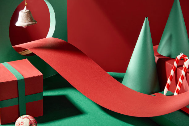 一张宽大的红色纸张折叠成弯曲的形状，穿过一个圆形切口的道路，露出一个悬挂的铃铛。圣诞照片中到处都是诺埃尔装饰。图片下载