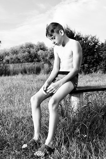 一个穿着泳裤的少年在河里游泳后坐在长椅上。黑白照片中，一个面露悲伤的孩子。图片下载