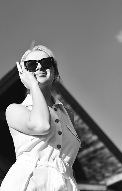 一位年轻女性戴着太阳镜，穿着白色西装的黑白照片。长发的漂亮金发模特肖像。图片下载
