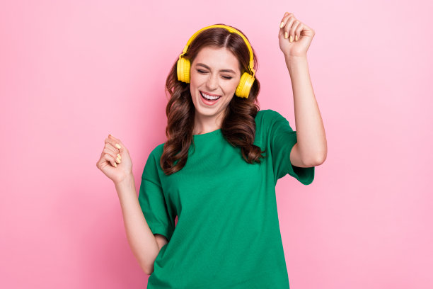 特写照片，快乐积极的女DJ穿着时尚的绿色服装，心情愉悦，背景为粉色。图片下载