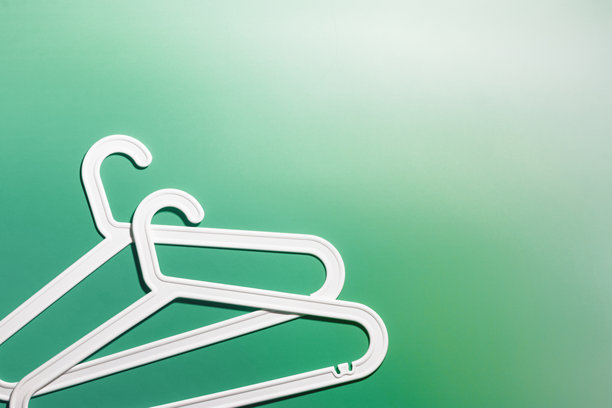 两个白色衣架，现代简约构图，背景为鲜艳的绿色渐变，塑料架营造出现代简约的美感，俯视图，平铺创意照片，留白空间图片下载