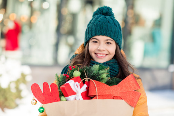 穿风衣的快乐搞笑女学生在城市街道上购买圣诞礼物的照片图片下载