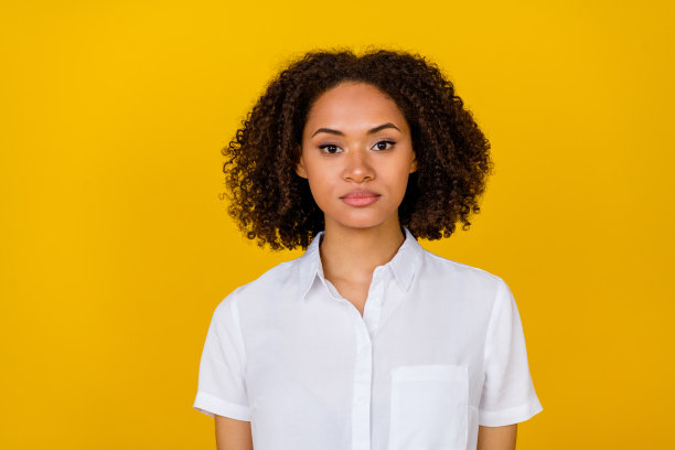 时尚的女性近距离照片，卷发造型，穿着潮流服饰，会议结束后在黄色背景下拍摄。图片下载