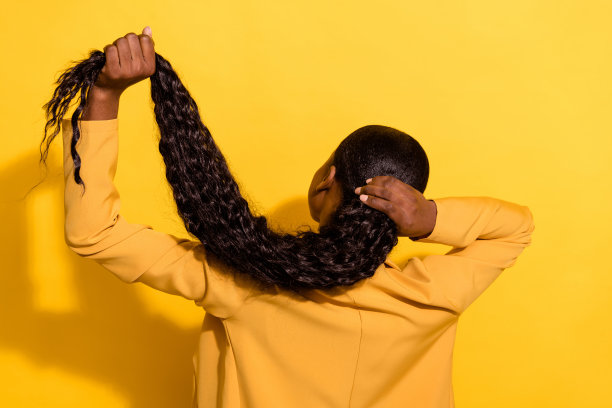 背影照片，波浪卷发的千禧美女穿着夹克，背景为黄色。图片下载