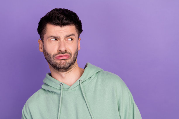 特写照片：年轻的搞笑学生，棕色短发，撅嘴看向空旷的空间，显得不满意，不喜欢的信息，背景为紫色。图片下载