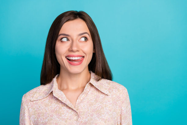 时尚漂亮女士的特写照片，穿着流行的上衣，露出感兴趣的表情，舔着牙齿，似乎在享受美味，背景为青色。图片下载