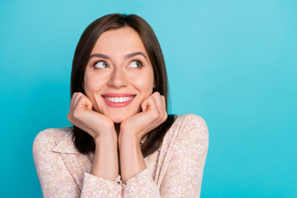 特写照片，迷人的年轻女士看起来梦幻，空灵，穿着时尚的休闲服，背景为海蓝色。图片下载