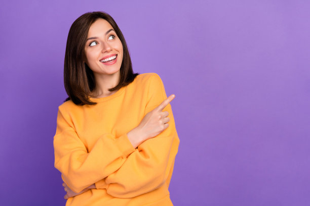 特写照片，迷人满意的女士穿着时尚的橙色毛衣，手臂指向空旷的空间，酷炫的提议，背景为紫色。图片下载