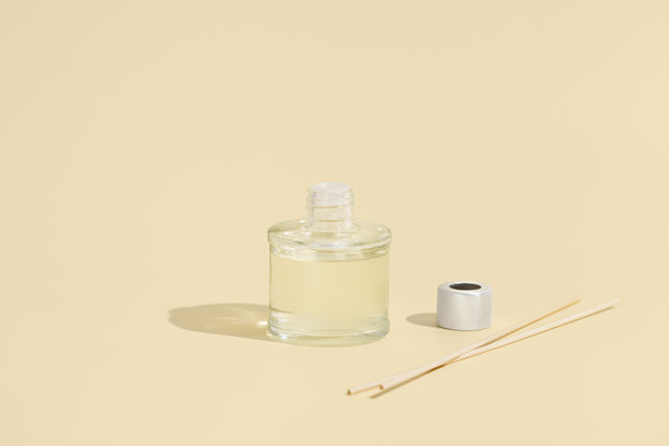 透明玻璃香氛瓶，配有藤条，背景为米色。装饰、舒适生活和芳香疗法概念。家用香薰条。适合您的设计的图片。图片下载