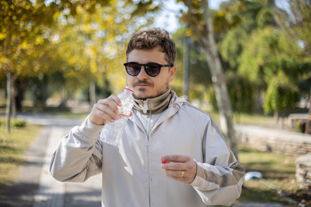 在公园跑步后喝水的男子库存照片图片下载