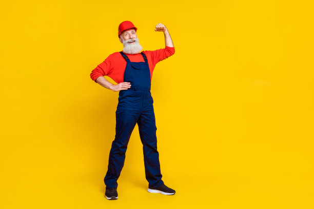自信的工人祖父在明亮的背景下展示肱二头肌，修理建筑物的全身照片图片下载