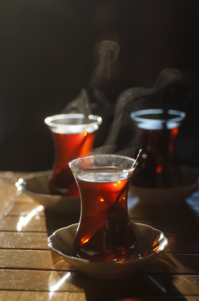美丽的逆光照片，浅景深，热腾腾的土耳其茶在传统玻璃杯中盛放，摆放在木桌上。图片下载
