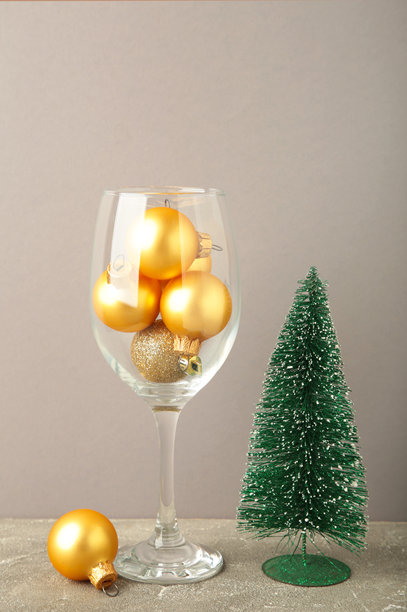 灰色背景上的酒杯与圣诞球。竖版照片图片下载