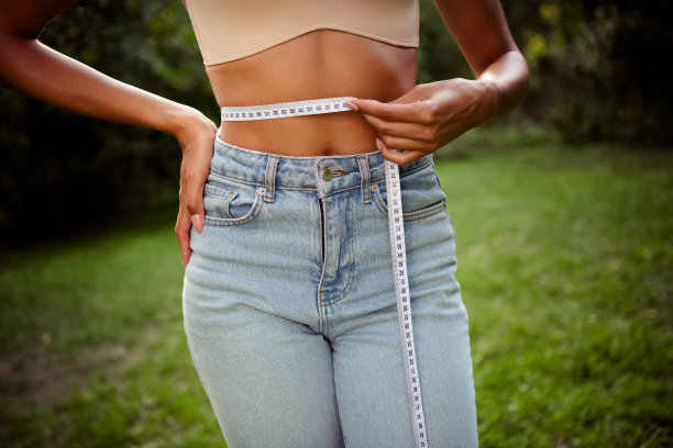 年轻可爱的纤细女士在户外公园测量腹部尺寸的裁剪照片图片下载