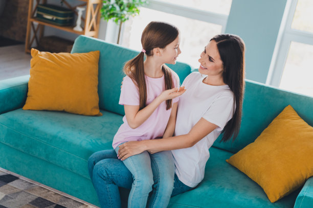 积极可爱的女儿在公寓客厅与穿着休闲服的妈妈交谈的照片图片下载