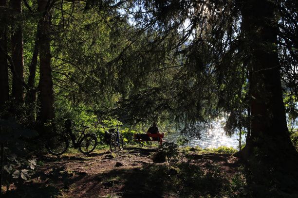 湖边长椅上坐着的骑自行车者的逆光照片图片下载