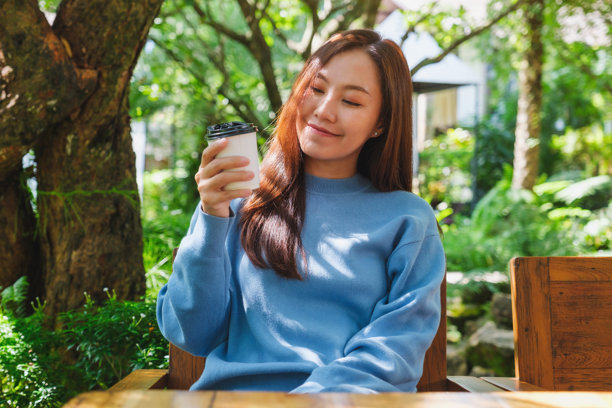 年轻女性在花园里手持咖啡并饮用的肖像照片图片下载