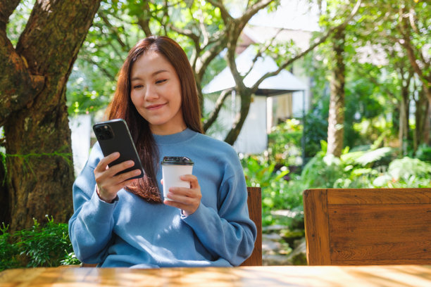 户外一位女性使用手机并喝咖啡的肖像照片图片下载
