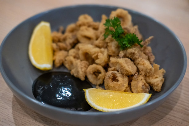盘子上盛着柠檬的炸鱿鱼特写照片。图片下载