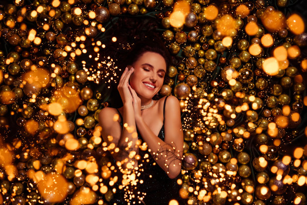 俯视照片中，时尚、精致、快乐的女孩躺在圣诞节明亮的装饰背景上。图片下载