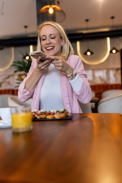 女性网红在餐厅拍摄食物照片。社交媒体。美食与饮品概念。图片下载