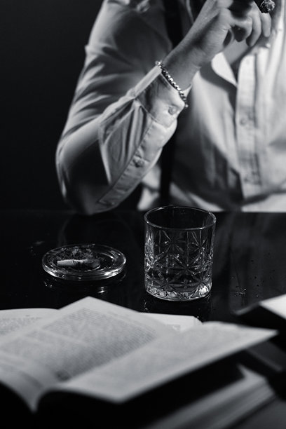 一名抽着雪茄的男子坐在椅子上，背景是寺庙，黑白照片。图片下载