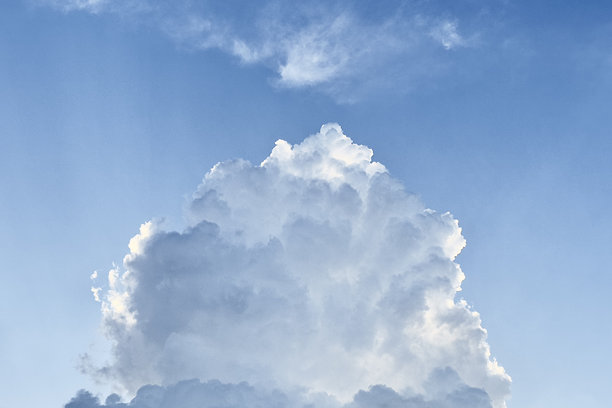 这张图片捕捉了一朵美丽、蓬松的云朵，背景是晴朗的蓝天。云朵浓密且轮廓分明，边缘柔和，展现了典型的积云膨胀形状。鲜艳的蓝色图片下载