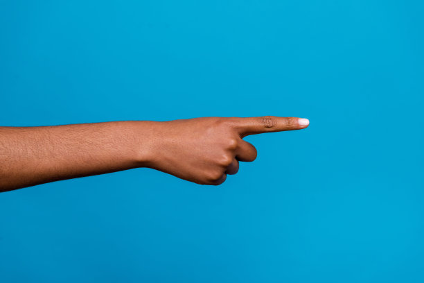 女人的手指指向空白区域的特写照片，背景为蓝色。图片下载