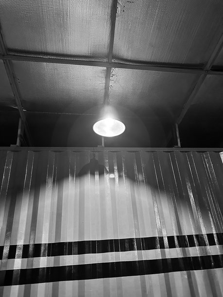 黑白照片，天花板灯光在波纹金属墙上投射阴影图片下载