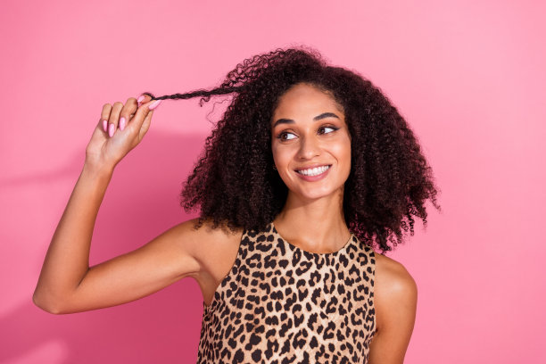 漂亮年轻女孩的照片肖像，手持一束洗发水，穿着时尚的豹纹服装，背景为粉色。图片下载