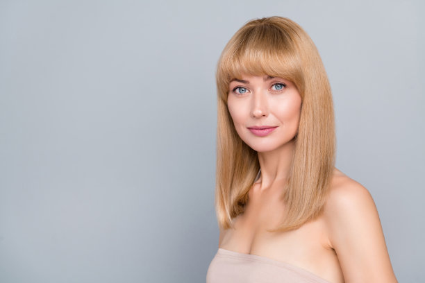 侧面肖像照片，女士站在空旷的空间中，宣传美容师的丝滑柔软护理，背景为灰色。图片下载