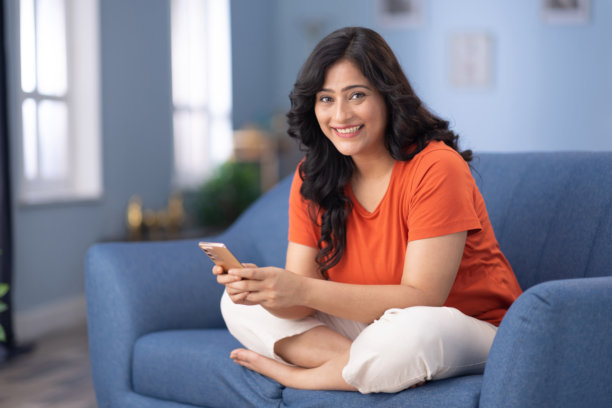 女人在家沙发上坐着使用手机的照片图片下载