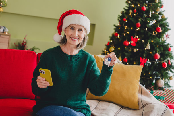 积极可爱的祖母手握钥匙，庆祝新年魔法礼物，购买新公寓的照片图片下载