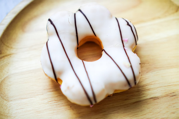 清迈，泰国厨房中木盘上的简单白糖霜甜甜圈照片。图片下载