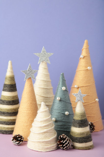 紫色背景上的手工圣诞树。用毛线包裹的锥形树。DIY概念。竖版照片图片下载