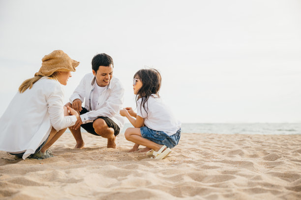 父亲和他的两个女儿在海滩上快乐地堆沙堡的照片图片下载