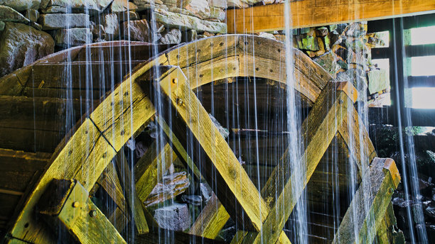 古老的木制水车被落水溅起的水花打湿。瑞典水磨坊的照片图片下载