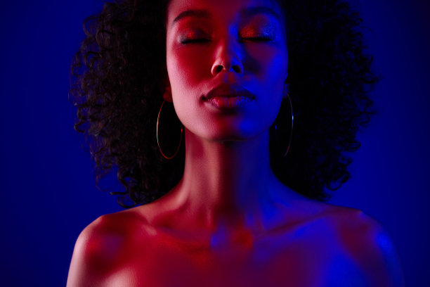特写照片，展现一位美丽的女士，闭着眼睛，露出的肩膀，背景为蓝色霓虹色。图片下载
