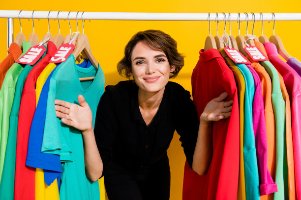 穿着黑色衬衫的漂亮快乐女士在黄色背景下的购物展厅工作照片图片下载