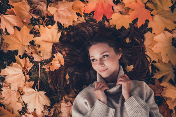 俯视图照片，展现了一位可爱的女士，手臂轻触针织衣领，梦幻般地想象着户外的闲暇时光。图片下载