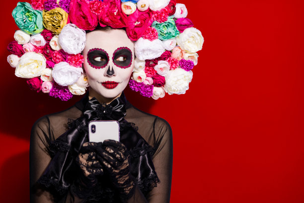 特写照片：死去的卡瓦列里塔女士，派对民俗宗教面具，面部骷髅图案，电话博客，亡灵节传统，侧面看，花卉头带，黑色服装，紫色背景隔离。图片下载