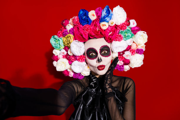 特写照片，展示有趣的传统民俗女巫死亡日面具，面部化妆令人毛骨悚然，适合化妆舞会的拉丁节日，佩戴花卉头饰的服装，背景为紫色，适合自拍。图片下载